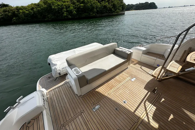  Yacht Photos Pics 2023 Fairline Squadron 50 yacht deck with seating, overlooking serene water and lush greenery.