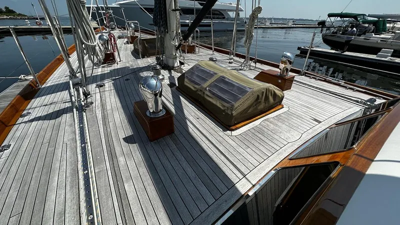 Nala Yacht Photos Pics Deck of 2004 Lyman-Morse Sparkman & Stephens Sloop, featuring sleek wooden design and marina backdrop.