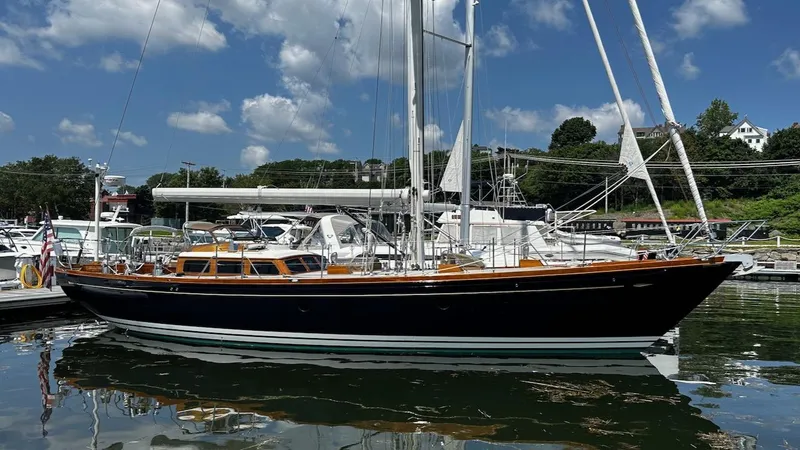 Nala Yacht Photos Pics 2004 Lyman-Morse Sparkman & Stephens Sloop docked, reflecting on calm water under a blue sky.