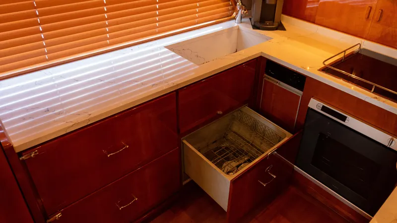 Chill 'n Yacht Photos Pics Luxurious kitchen interior of 2003 Bertram 67 Convertible yacht with wooden cabinets and modern appliances.