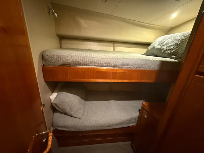 Chill 'n Yacht Photos Pics Bunk beds in 2003 Bertram 67 Convertible yacht cabin, featuring wooden finishes and cozy bedding.