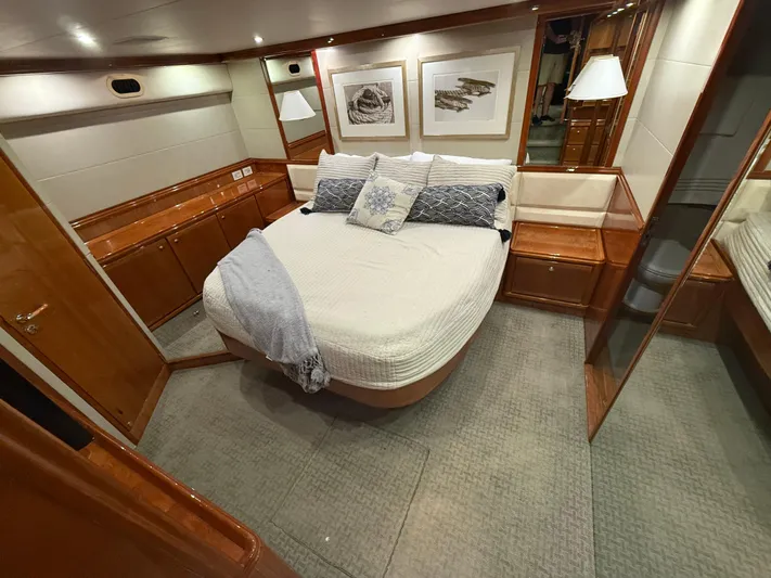 Chill 'n Yacht Photos Pics Luxurious bedroom interior of 2003 Bertram 67 Convertible yacht with elegant wood finishes.