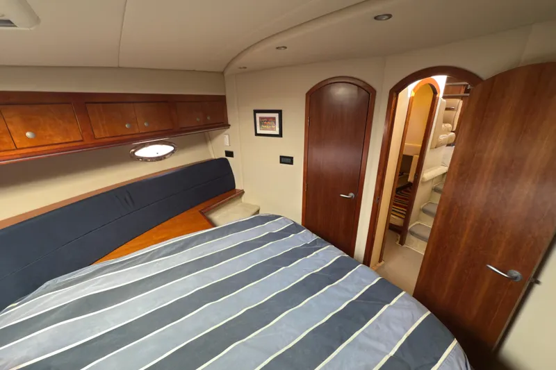  Yacht Photos Pics Luxurious 2008 Cruisers 455 Motor Yacht bedroom with striped bedding and wooden cabinetry.