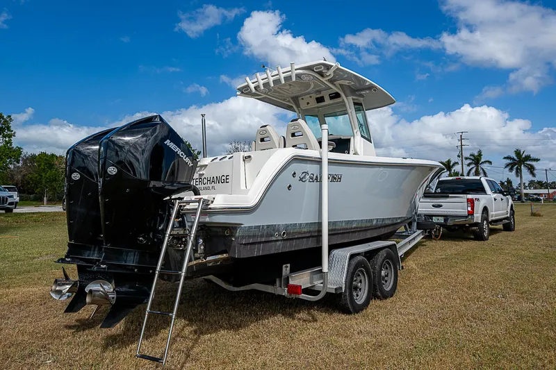  Yacht Photos Pics 2022 Sailfish 272CC boat on trailer, parked on grass under blue sky.