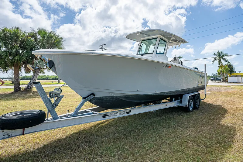  Yacht Photos Pics 2022 Sailfish 272CC boat on trailer, parked on grass under cloudy sky.