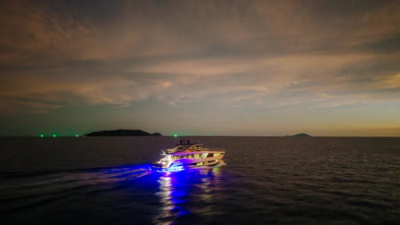  Yacht Photos Pics Luxurious 2023 Princess Y95 yacht illuminated on the ocean at dusk.