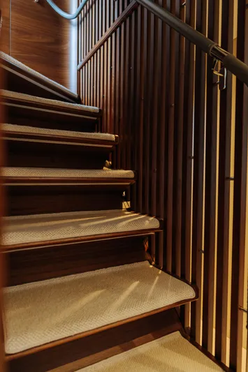  Yacht Photos Pics Luxurious wooden staircase inside 2023 Princess Y95 yacht, featuring elegant design and soft lighting.