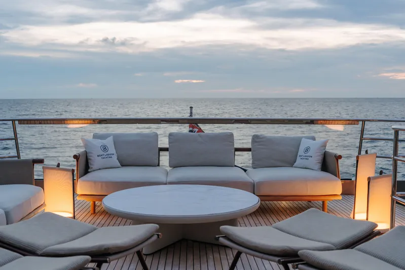  Yacht Photos Pics Luxurious 2023 Princess Y95 yacht deck with elegant seating and ocean view at sunset.