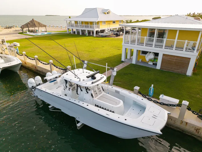  Yacht Photos Pics 2024 Freeman 38 boat docked near yellow waterfront house with lush green lawn.