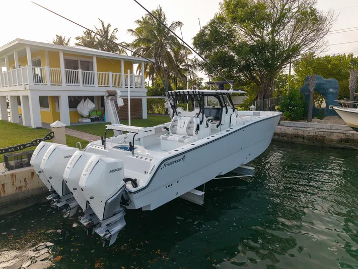  Yacht Photos Pics 2024 Freeman 38 boat docked near a waterfront house with palm trees.