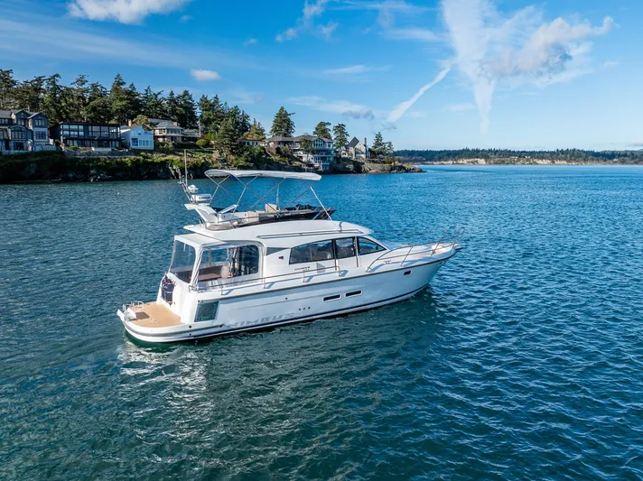 Duet Yacht Photos Pics 2024 Nimbus 405 Flybridge yacht cruising on a scenic blue lake near a forested shoreline.