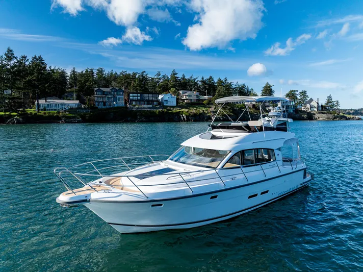 Duet Yacht Photos Pics 2024 Nimbus 405 Flybridge yacht cruising on a scenic lake with houses and trees in the background.