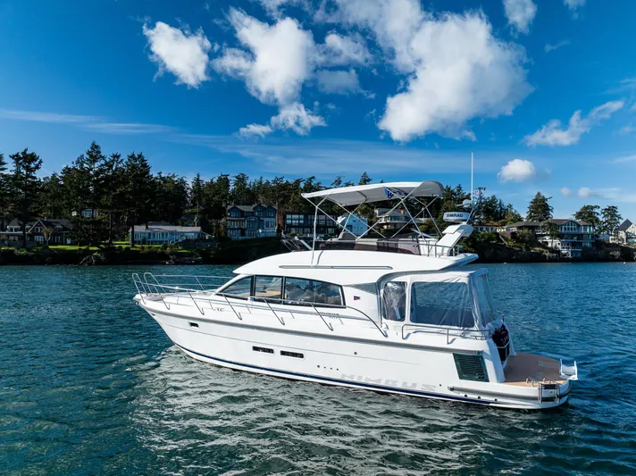 Duet Yacht Photos Pics 2024 Nimbus 405 Flybridge yacht cruising on a serene lake under a clear blue sky.