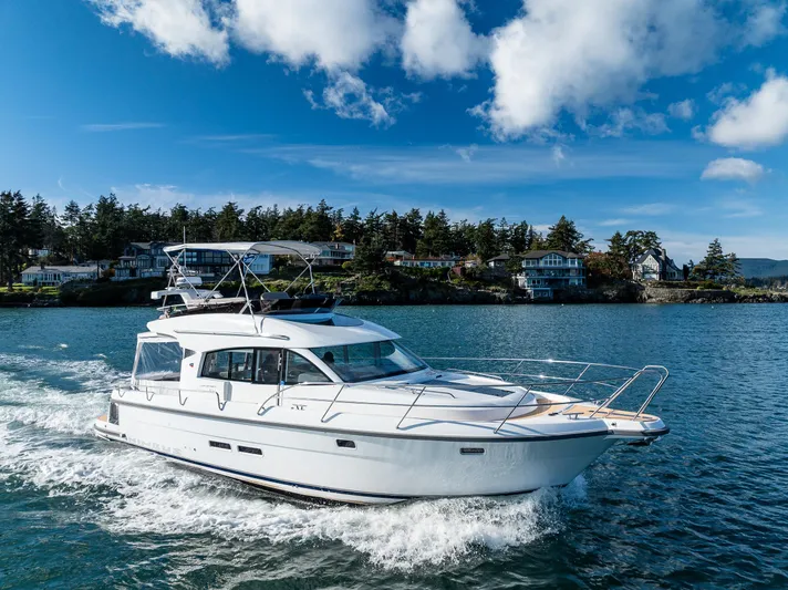 Duet Yacht Photos Pics 2024 Nimbus 405 Flybridge cruising on a scenic lake under a clear blue sky.