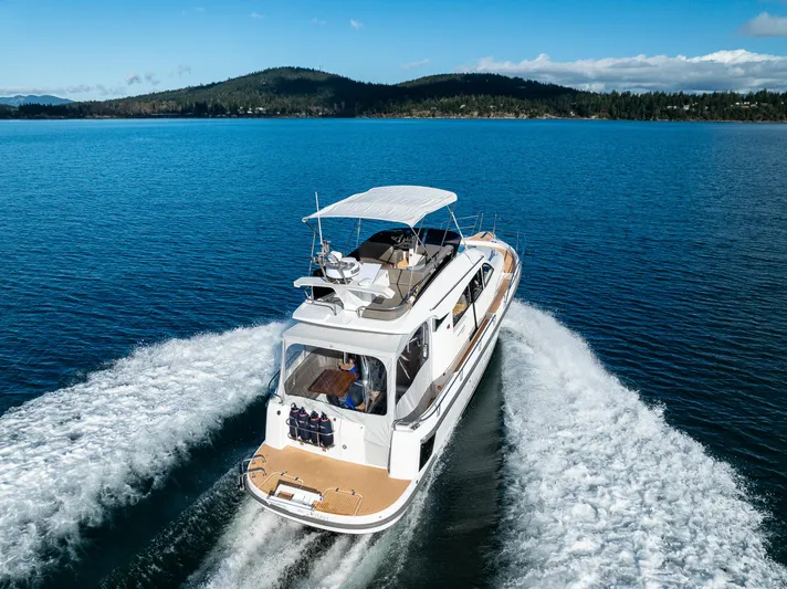 Duet Yacht Photos Pics Nimbus 405 Flybridge 2024 cruising on a serene lake with scenic mountain backdrop.