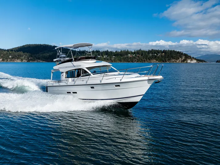 Duet Yacht Photos Pics 2024 Nimbus 405 Flybridge cruising on a scenic lake under a clear blue sky.