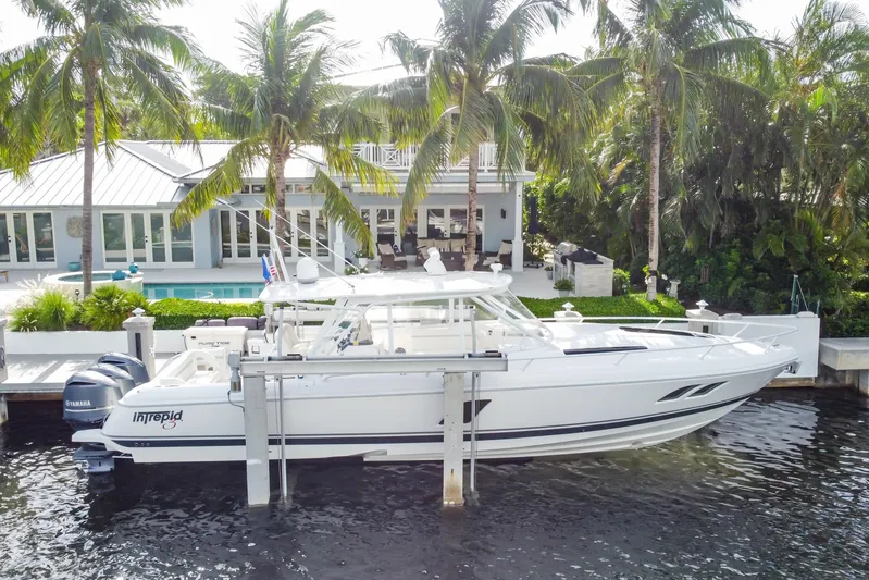  Yacht Photos Pics 2016 Intrepid 400 Cuddy boat docked by a waterfront home with palm trees.
