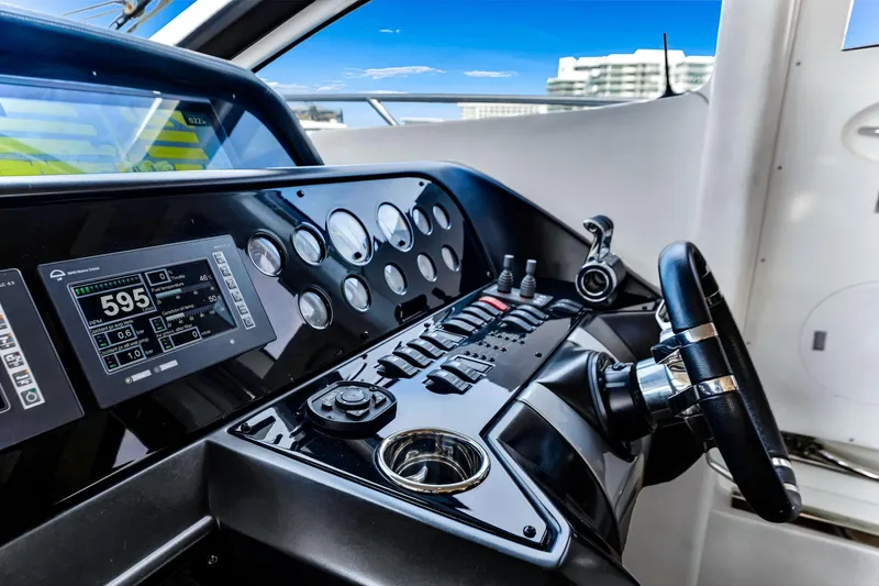 Jimbo Yacht Photos Pics Control panel of a 2012 Sunseeker 74 Sport Yacht with steering wheel and digital displays.
