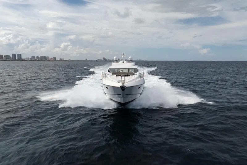 Jimbo Yacht Photos Pics Sunseeker 74 Sport Yacht 2012 cruising on open water, city skyline in background.