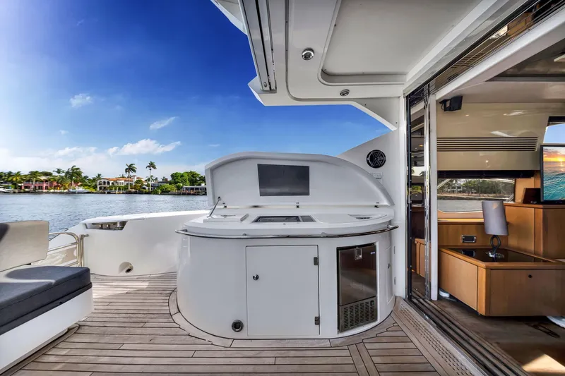 Jimbo Yacht Photos Pics Luxurious Sunseeker 74 Sport Yacht deck with outdoor kitchen, overlooking serene waterfront.