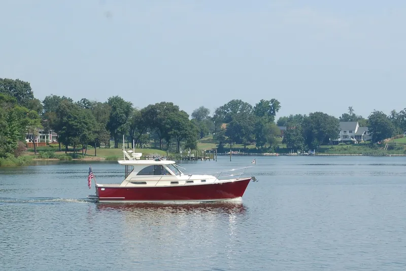 Off Islander Yacht Photos Pics 2007 Legacy Yachts 32 cruising on a serene lake with lush green shoreline.