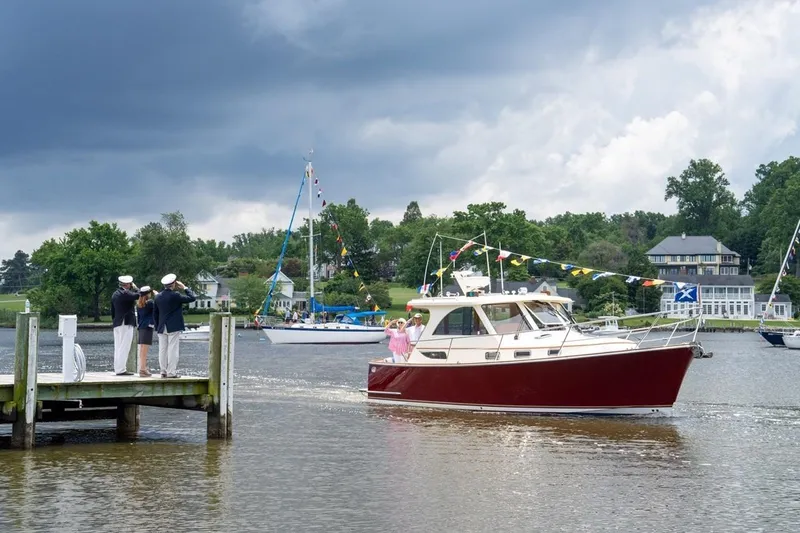 Off Islander Yacht Photos Pics 2007 Legacy Yachts 32 cruising near a dock with people saluting, under a cloudy sky.