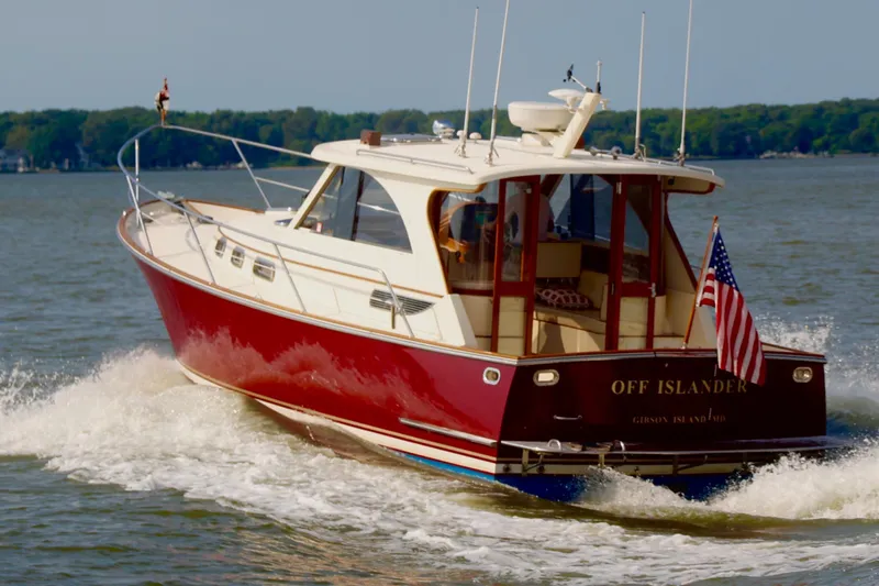 Off Islander Yacht Photos Pics 2007 Legacy Yachts 32 cruising on water, displaying American flag, lush green shoreline in background.