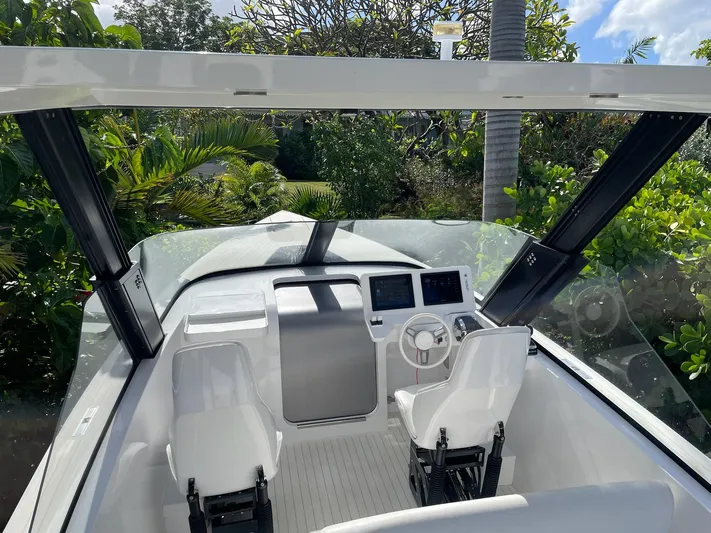 White Turtle Yacht Photos Pics 2019 Iguana Commuter boat interior with dual seats and dashboard, surrounded by lush greenery.