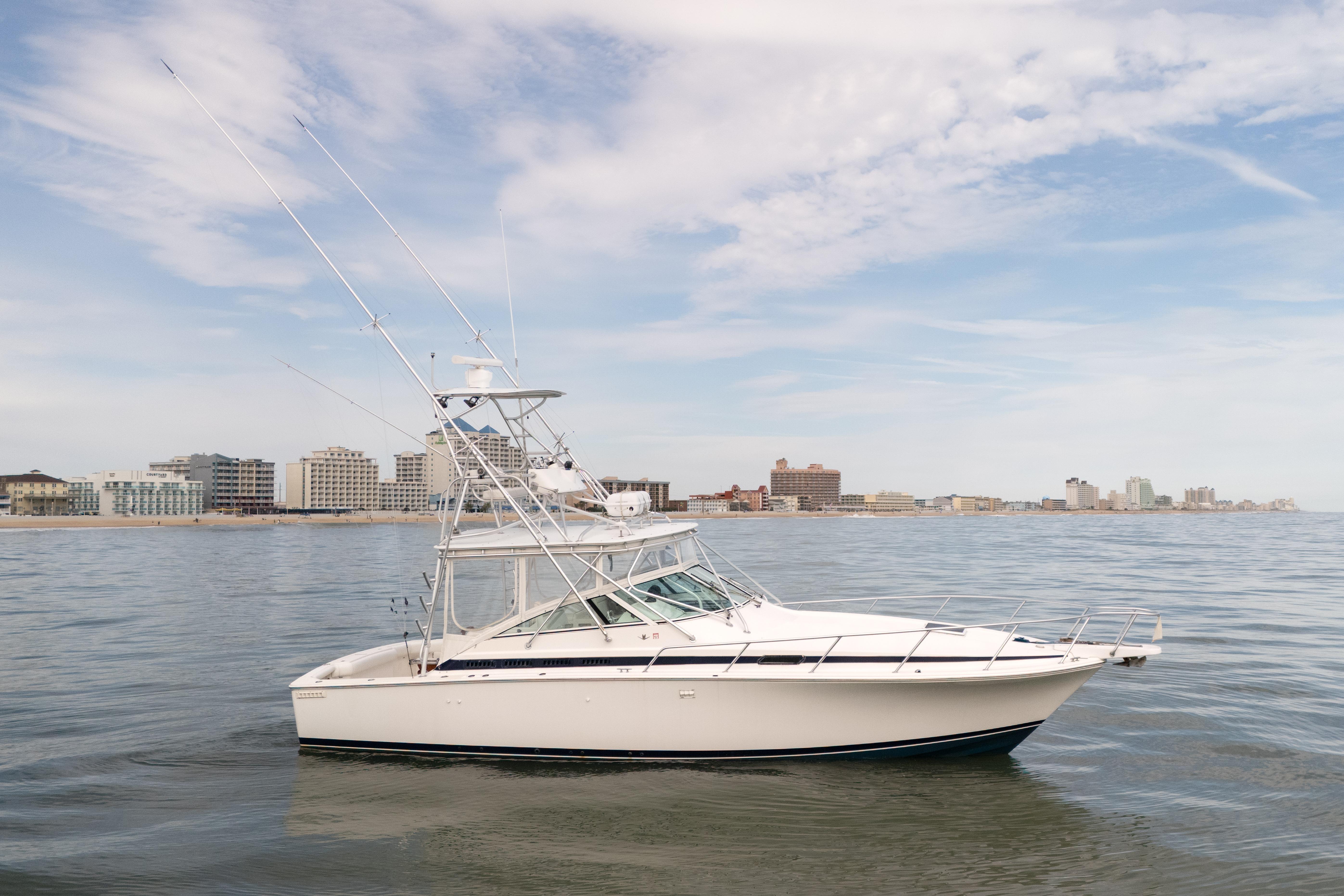 1998 Bertram 36 Moppie boat on calm water with city skyline in background.
