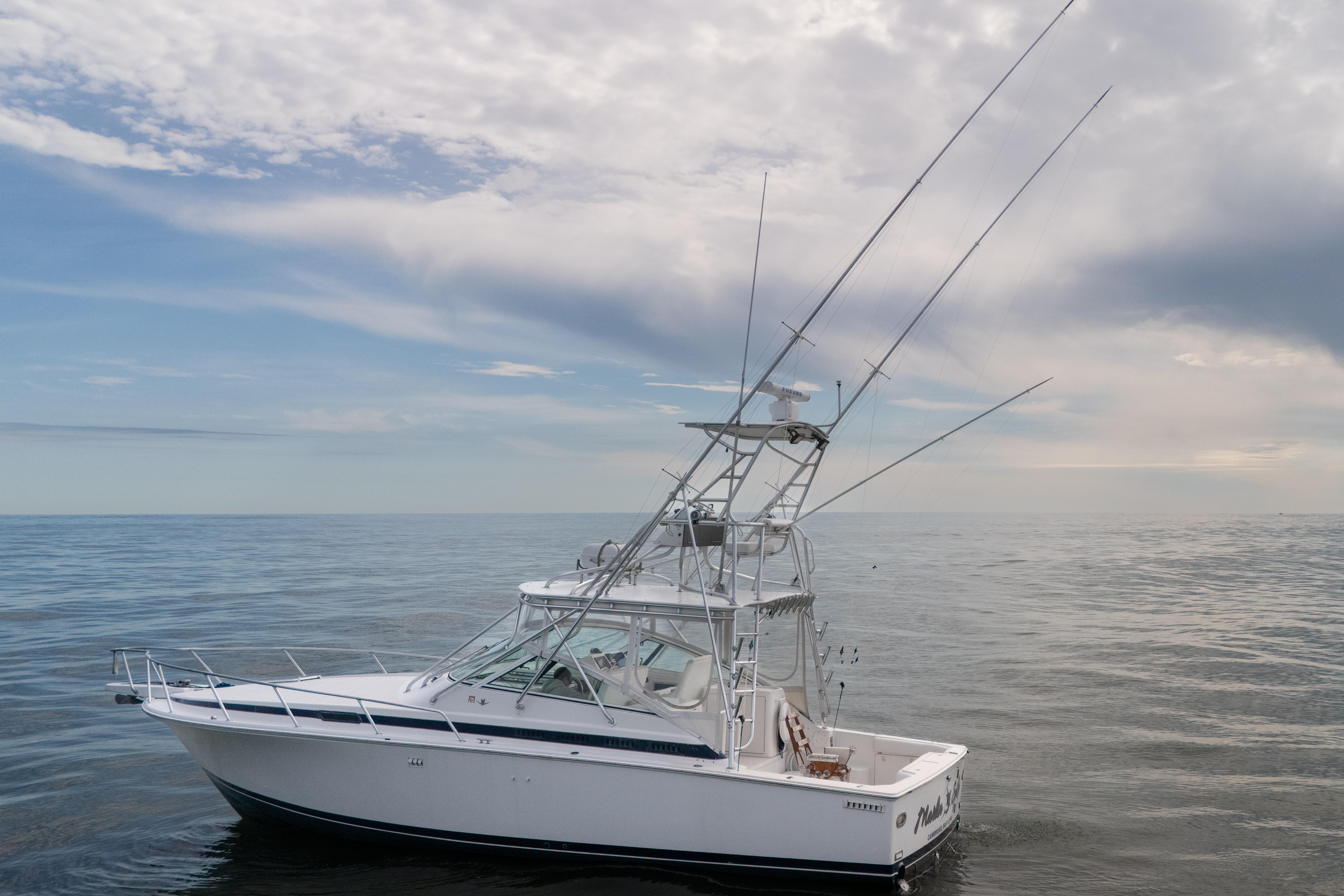 1998 Bertram 36 Moppie boat on calm ocean under cloudy sky.
