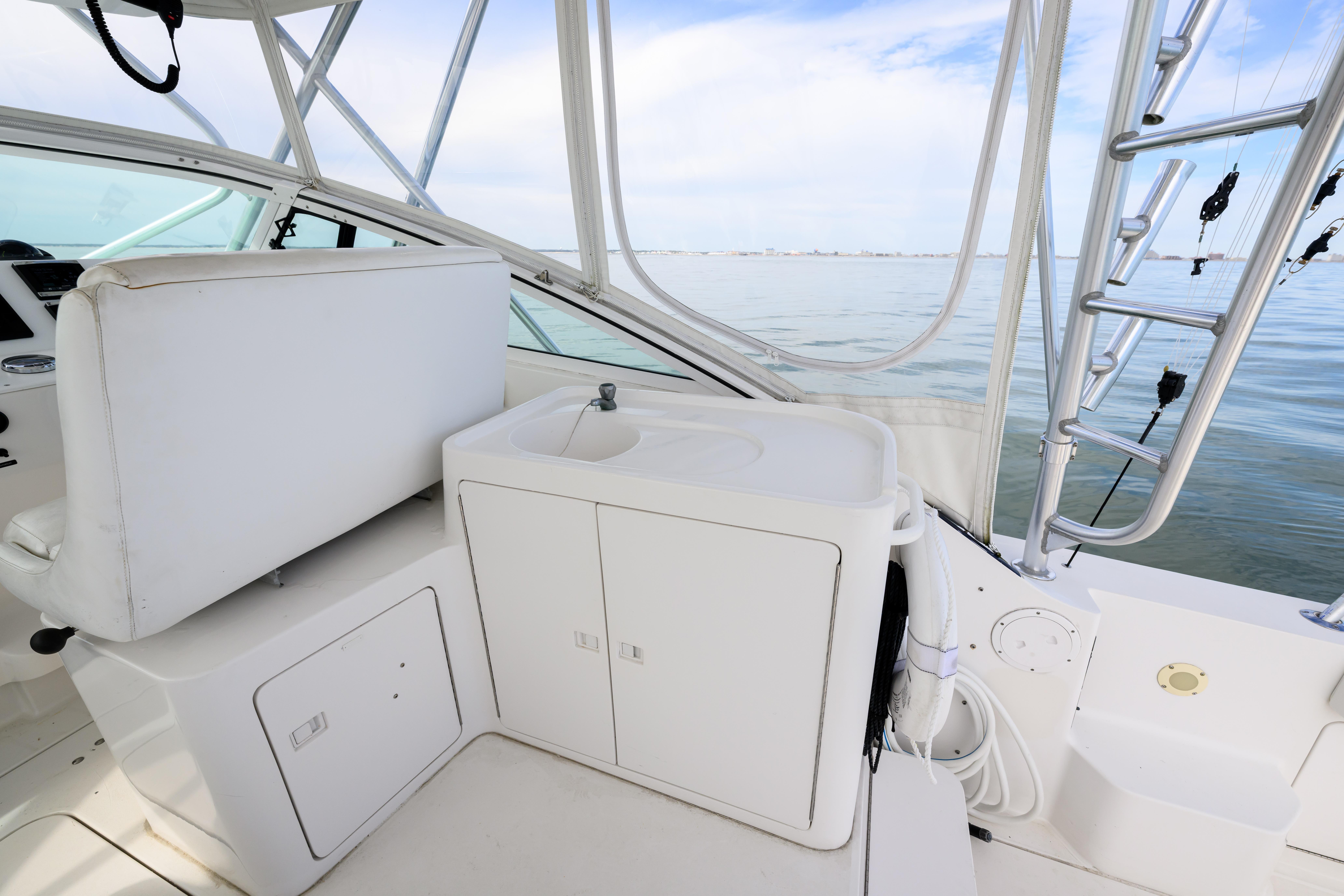 1998 Bertram 36 Moppie boat interior with white seating and sink, overlooking calm waters.