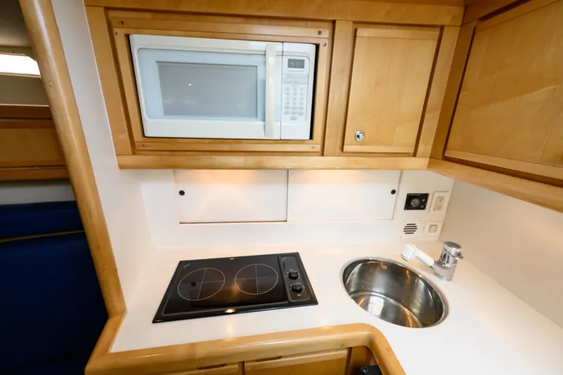 Marlin Spike Yacht Photos Pics Compact kitchen area in a 1998 Bertram 36 Moppie yacht with microwave and stovetop.