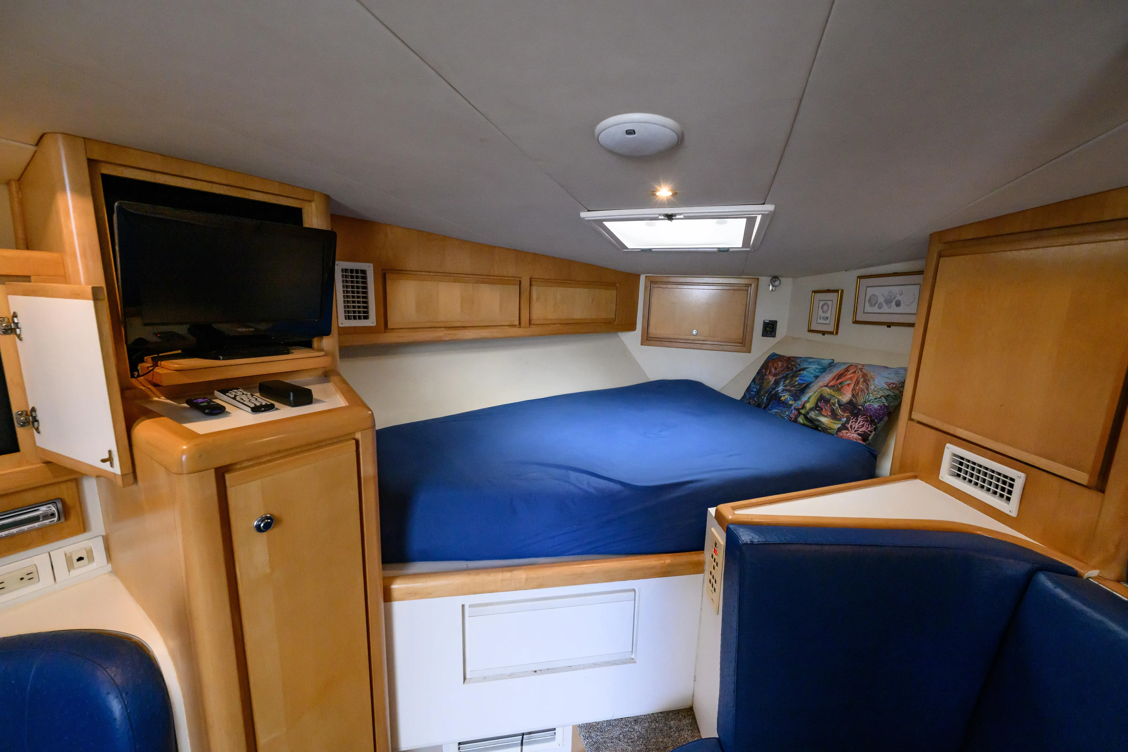 Marlin Spike Yacht Photos Pics Cozy cabin interior of 1998 Bertram 36 Moppie with bed, TV, and wooden cabinetry.