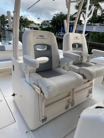  Yacht Photos Pics 2018 Cobia 320 CC boat with dual cushioned seats, docked near palm trees.