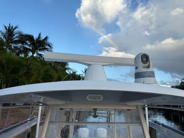  Yacht Photos Pics 2018 Cobia 320 CC boat with radar, docked near palm trees under a cloudy sky.