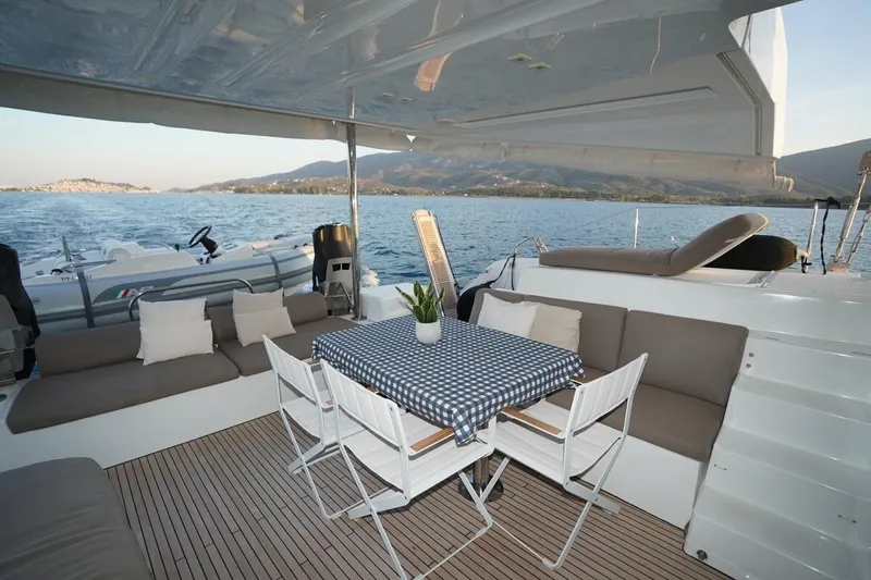  Yacht Photos Pics Luxurious 2022 Lagoon 50 catamaran deck with seating, table, and scenic ocean view.