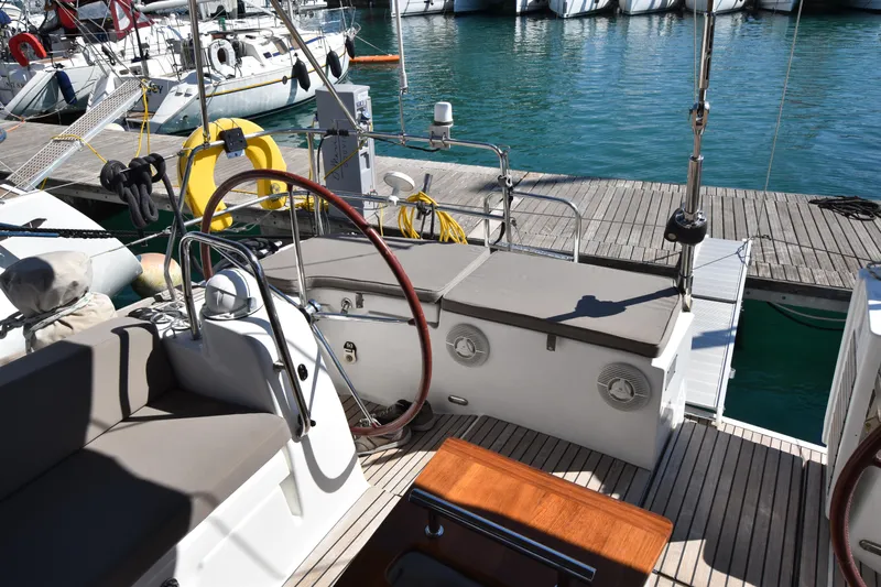 Panope Yacht Photos Pics Cockpit of 2009 Beneteau Oceanis 54 yacht docked at marina, featuring steering wheel and seating.