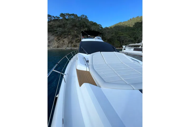 Escape Yacht Photos Pics 2014 Sunseeker 68 Sport Yacht with sleek deck design, docked near a forested shoreline.