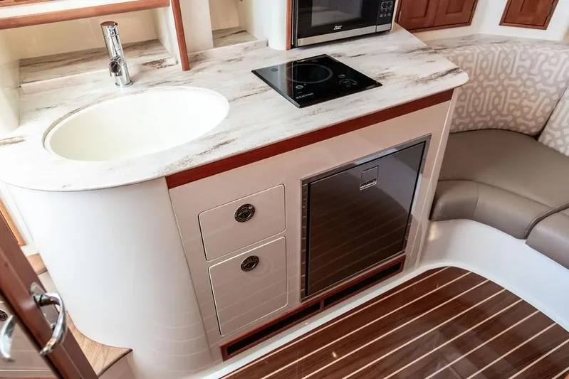 Stargazer Yacht Photos Pics 2024 Hinckley Sport Boat 40c interior with kitchenette, featuring sink, stove, and seating area.