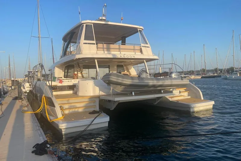 4ever VI Yacht Photos Pics 2022 Lagoon 67 yacht docked at marina, featuring spacious deck and tender boat.