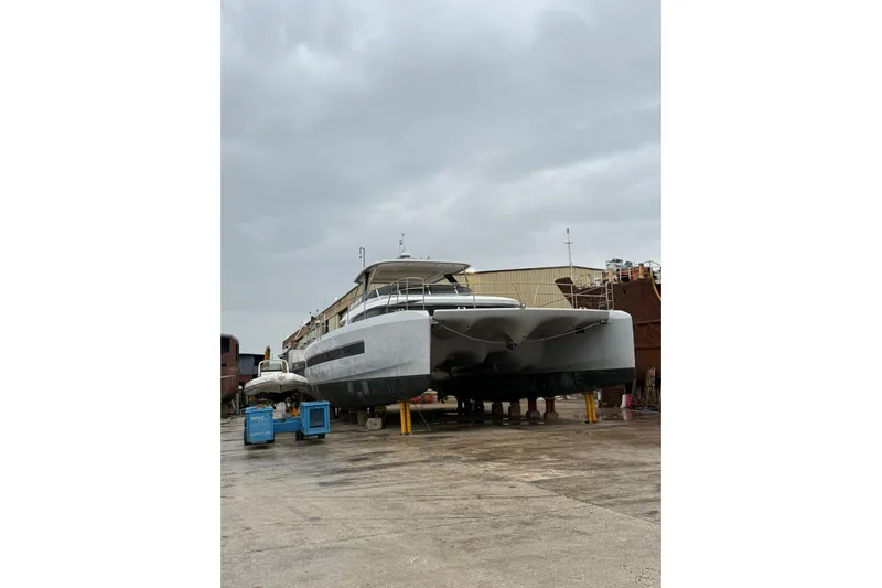 4ever VI Yacht Photos Pics 2022 Lagoon 67 catamaran on dry dock under cloudy skies.