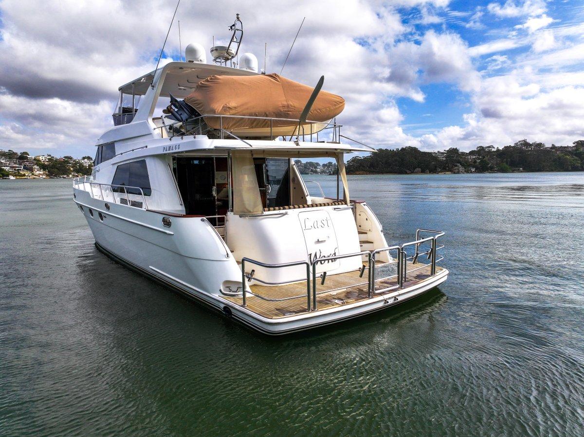 Luxury 2011 Pama 65 Pilot House yacht on calm water under a partly cloudy sky.