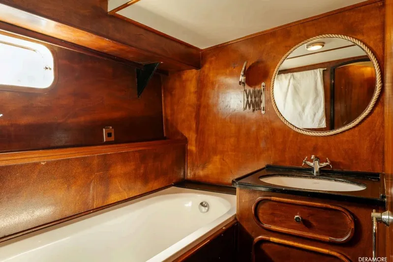 Deramore Yacht Photos Pics Luxurious wooden bathroom interior on 1971 Dagless Ambassador yacht, featuring bathtub and round mirror.