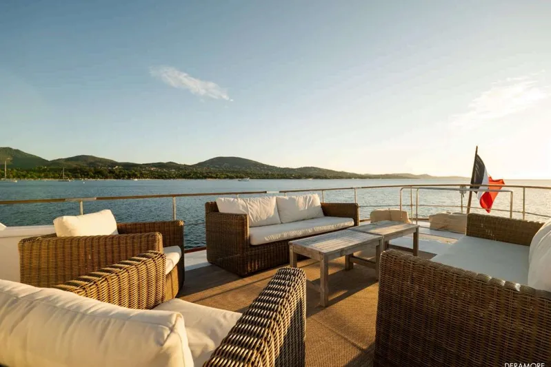 Deramore Yacht Photos Pics Luxurious 1971 Dagless Ambassador yacht deck with wicker furniture, overlooking serene waters and hills.