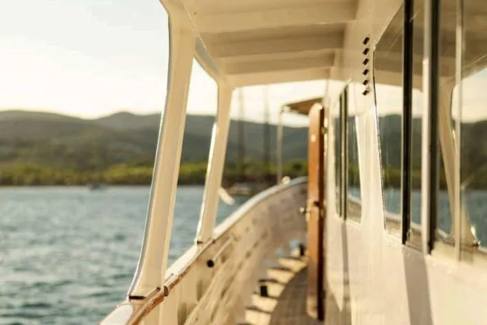 Deramore Yacht Photos Pics 1971 Dagless Ambassador yacht on serene water with scenic mountain backdrop.