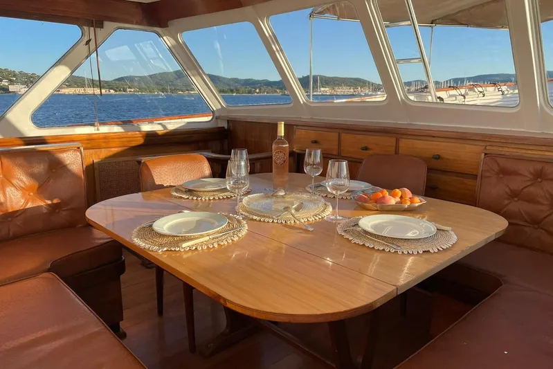Deramore Yacht Photos Pics Luxurious 1971 Dagless Ambassador yacht interior with elegant dining setup and scenic ocean view.