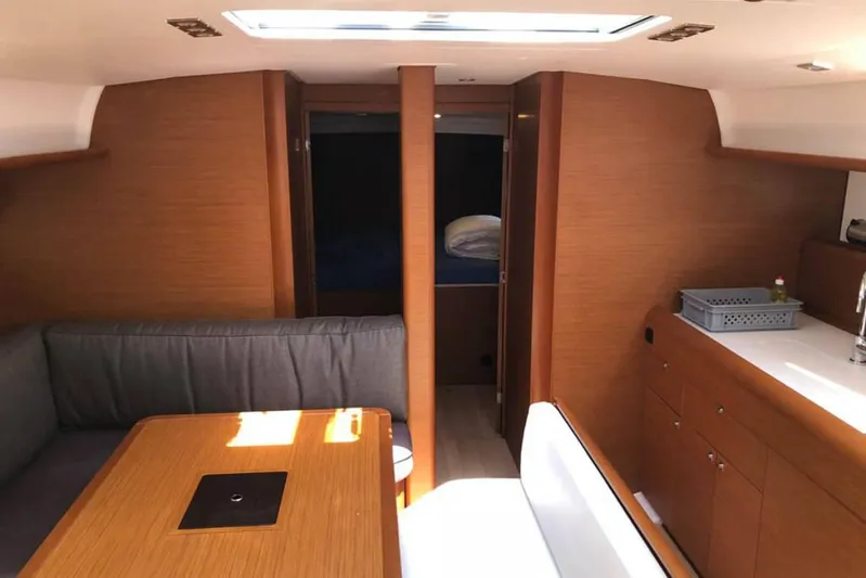Albinez Yacht Photos Pics Interior of 2018 Jeanneau Sun Odyssey 479 yacht, featuring wood finish and cozy seating area.