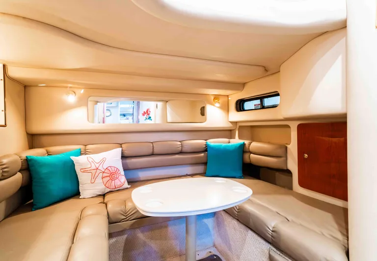  Yacht Photos Pics 1998 Sea Ray Sundancer 400 interior with beige seating, colorful pillows, and a white table.