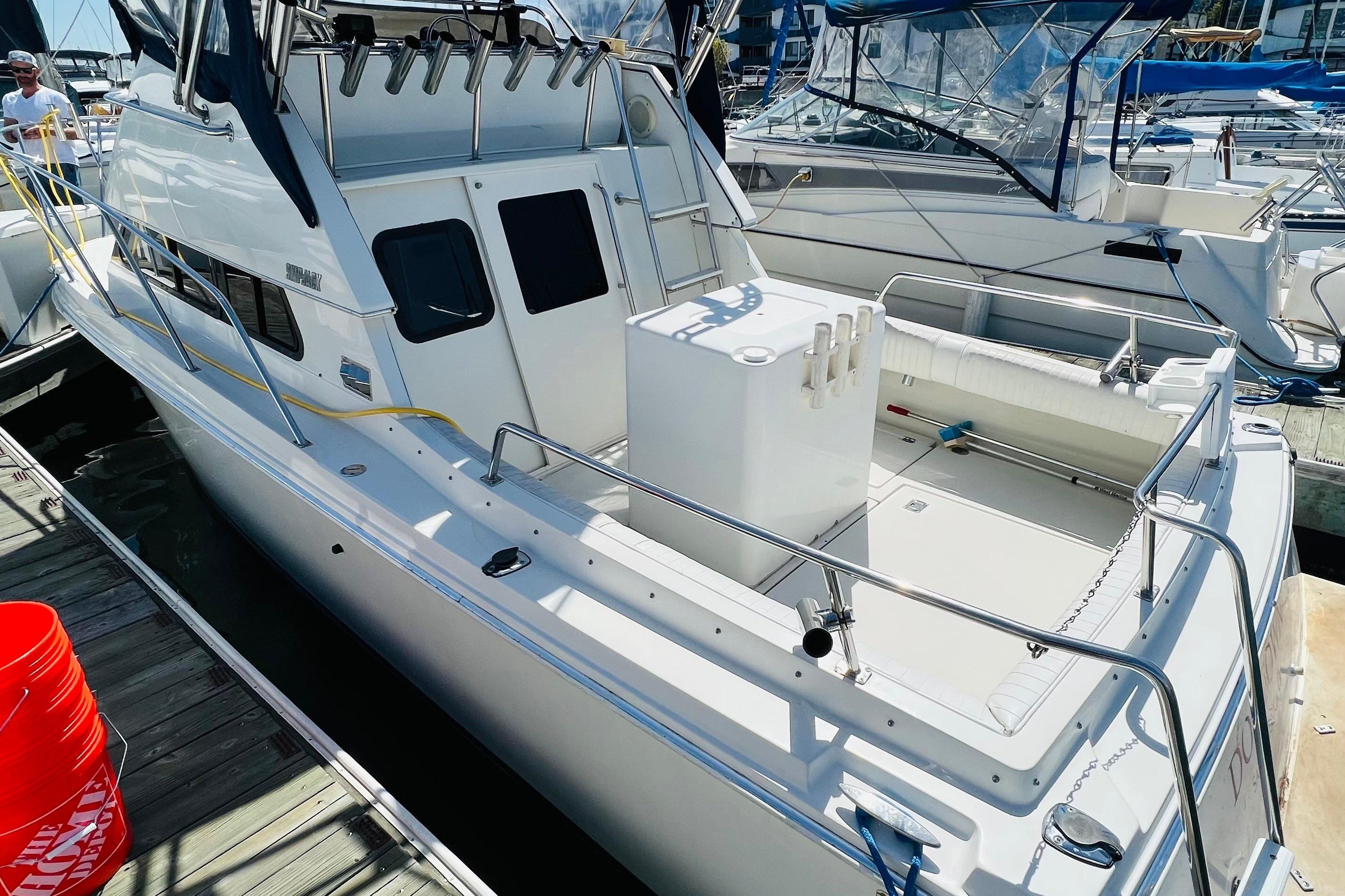 2001 Skipjack 262 Flybridge boat docked, featuring spacious deck and fishing rod holders.