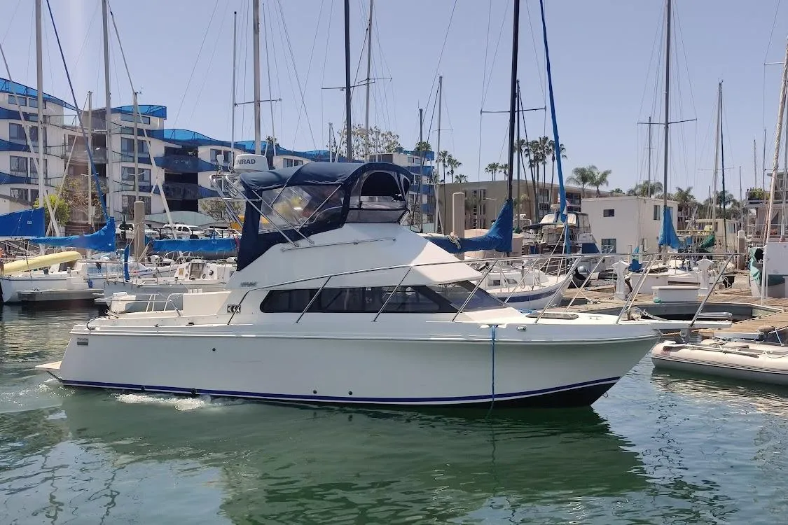 2001 Skipjack 262 Flybridge boat docked in a marina with sailboats.